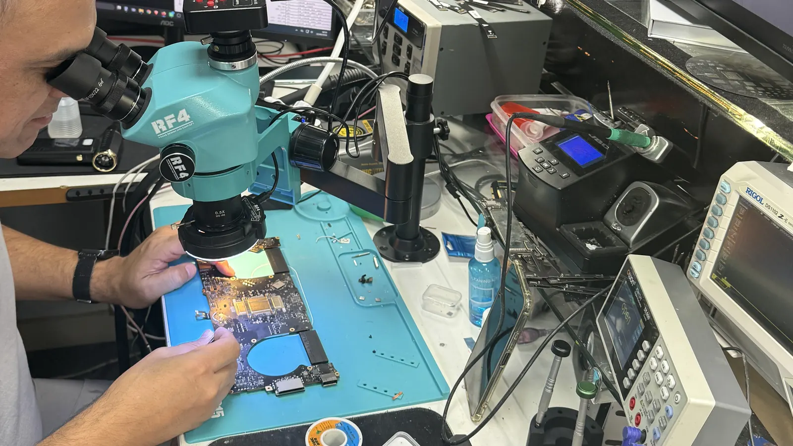 Técnico reparando una placa electrónica bajo microscopio en el taller de Alicante