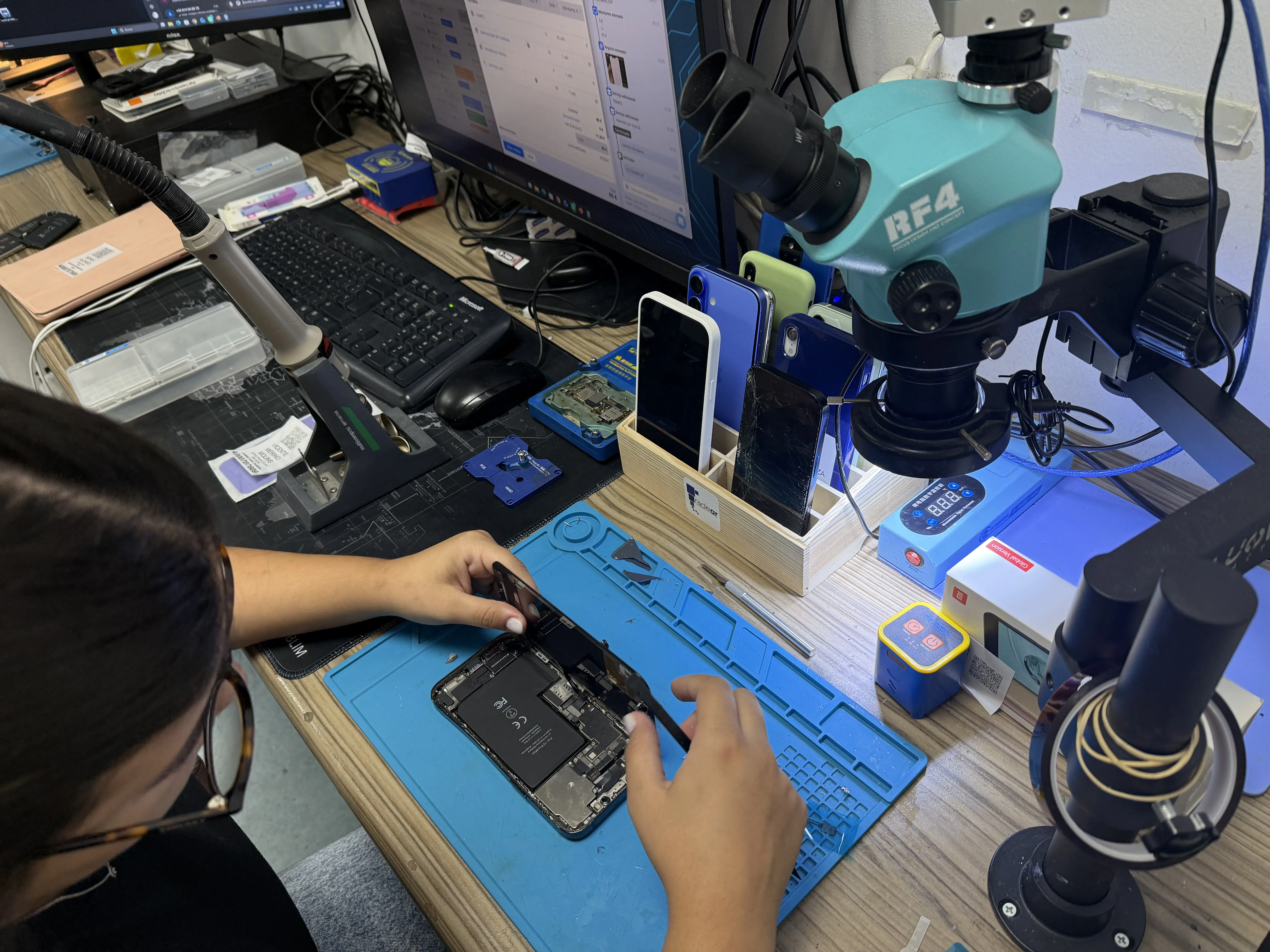 Técnico sustituyendo la pantalla de un teléfono móvil en el taller de Alicante